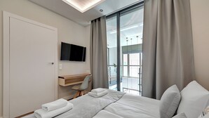 A modern hotel room with a large bed, a desk, and a TV. - Waterlane Riverside - SPA, Pool, Gym & Parking by Downtown Apartments (Gdansk)