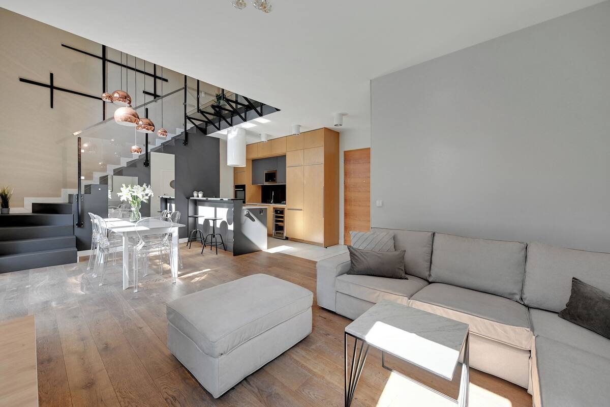A spacious living area with a staircase, a dining table, and a sofa.