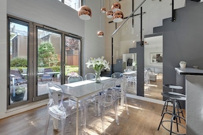 A modern dining area with a glass table and chairs, large windows, and a view of the outside. - Waterlane Riverside - SPA, Pool, Gym & Parking by Downtown Apartments (Gdansk)