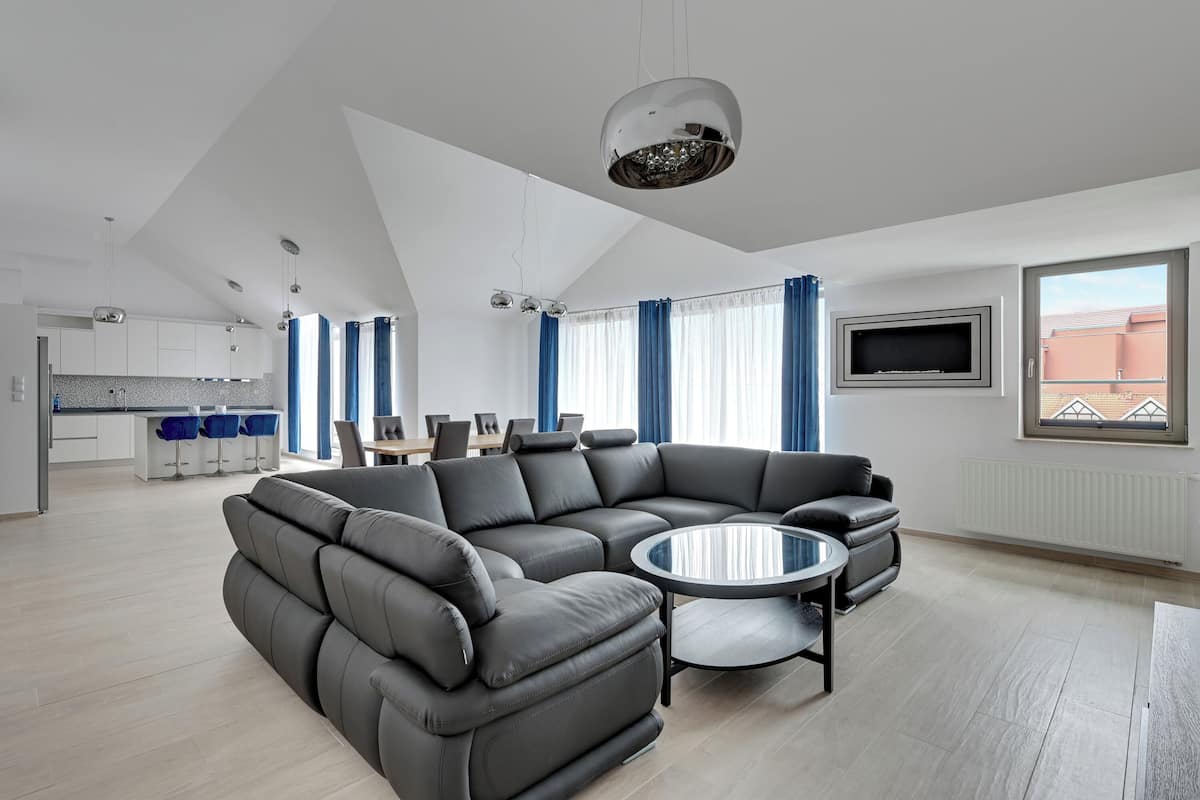 A modern living room with a sectional sofa, a round coffee table, and a TV mounted on the wall.