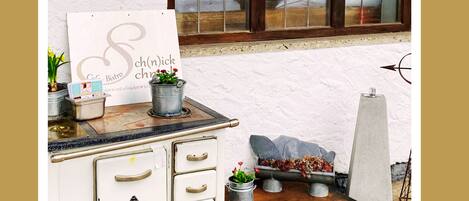A vintage-style kitchen with a signboard, potted plants, and a stone wall.