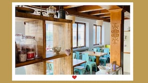 Un intérieur rustique avec des poutres en bois, une étagère en bois ornée de bocaux, une tasse à pois et des chaises de couleur turquoise.
