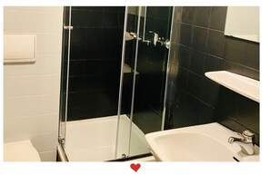 A bathroom with a glass-enclosed shower, a white sink, and a mirror.