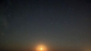 Una playa de noche con un mar tranquilo que refleja la luz de la luna.