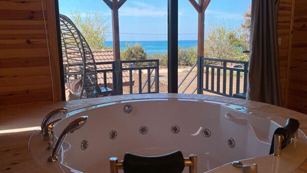 Una cabaña de madera con una bañera grande y vistas al océano.