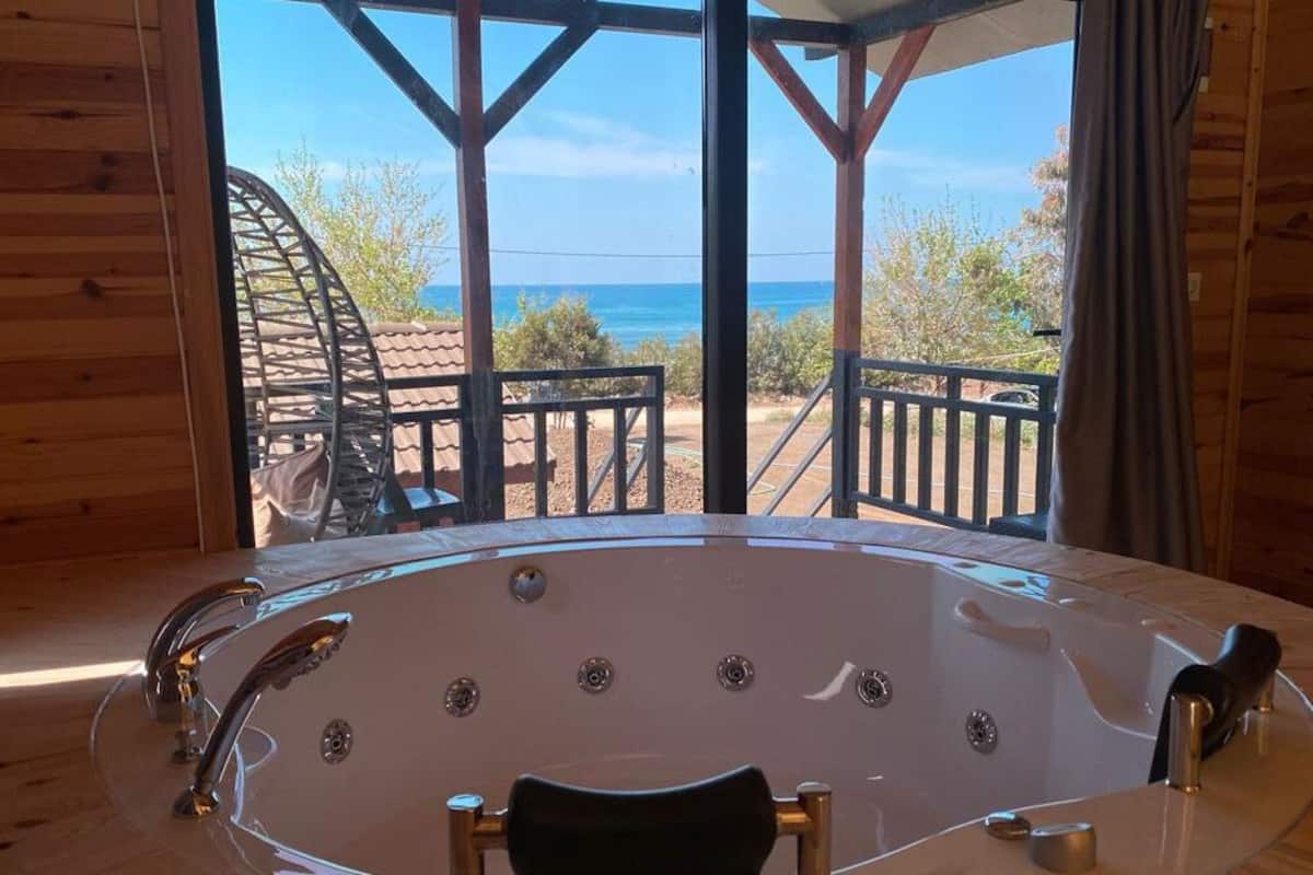 Eine Holzhütte mit einer großen Badewanne und Blick auf den Ozean.