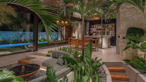 A modern interior with a wooden ceiling, a dining area, and a kitchen. - Cala Blanca (Munggu)