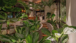 A lush indoor garden with a seating area, stone walls, and wooden beams. - Cala Blanca (Munggu)