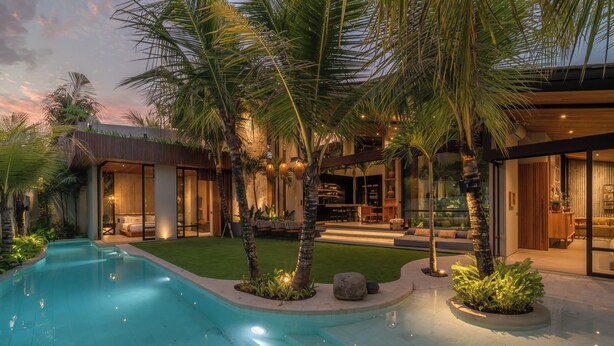 A modern house with a swimming pool, palm trees, and a well-lit outdoor area. - Cala Blanca (Munggu)