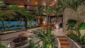 A modern indoor space with a pool, seating area, and kitchen. - Cala Blanca (Munggu)