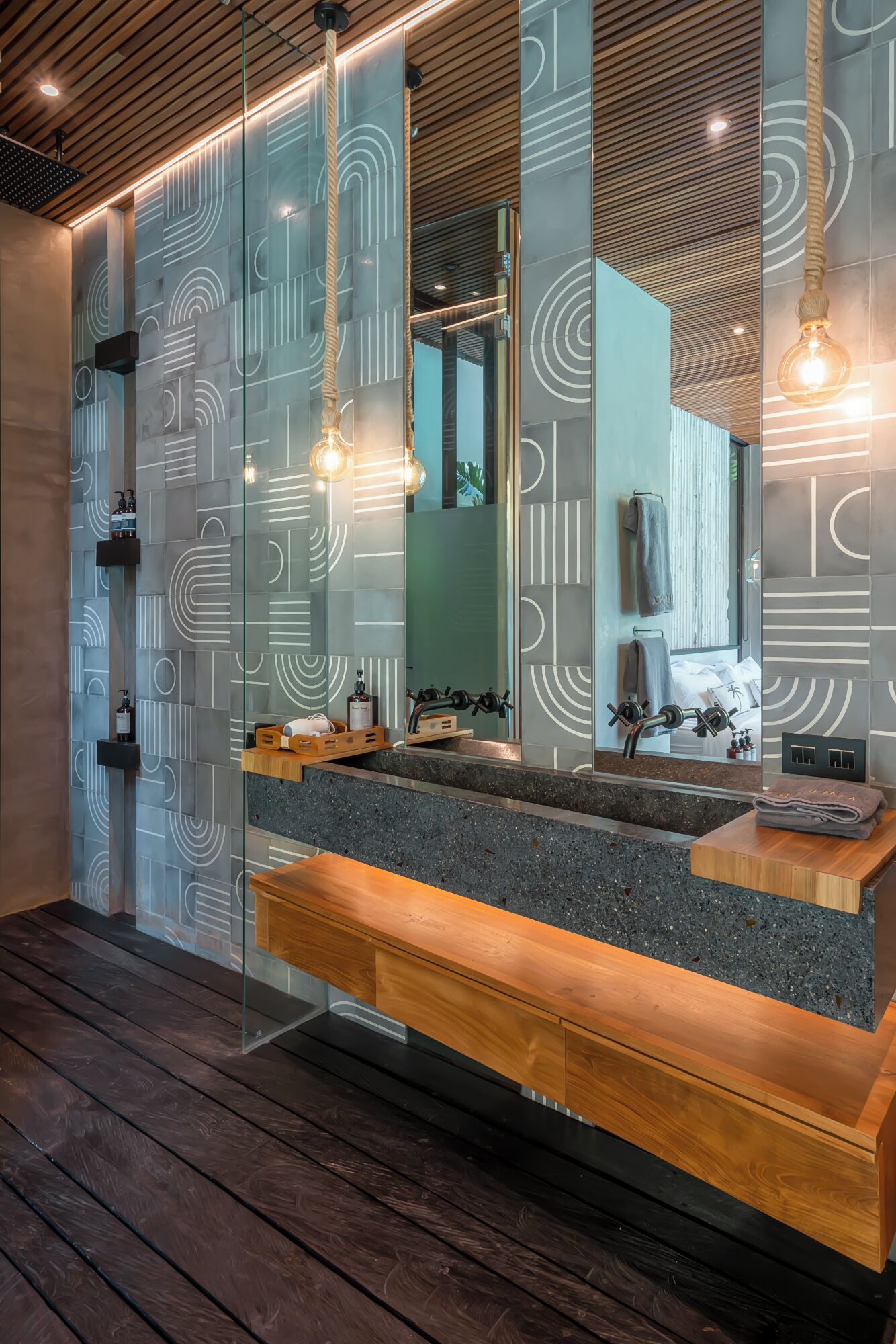 Un baño moderno con piso de madera, encimera de granito y un espejo grande.
