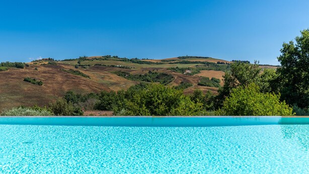 A clear blue swimming pool with a view of rolling hills and sparse vegetation in the background. - Luxury Private Villa Three Oaks W/ Star View - Beautiful Spot (Volterra)