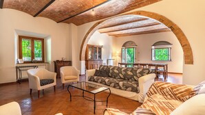 A spacious living area with a high ceiling, exposed brick arches, a sofa, armchairs, a coffee table, and a dining table. - Luxury Private Villa Three Oaks W/ Star View - Beautiful Spot (Volterra)