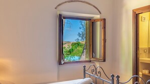 A bedroom with a bed, a window with a view of greenery, and a wooden door. - Luxury Private Villa Three Oaks W/ Star View - Beautiful Spot (Volterra)