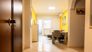 A hallway with a wooden door, a dining area with a table and chairs, and a kitchen area with a refrigerator. - Romantic Malatesta in Rome (Rome)