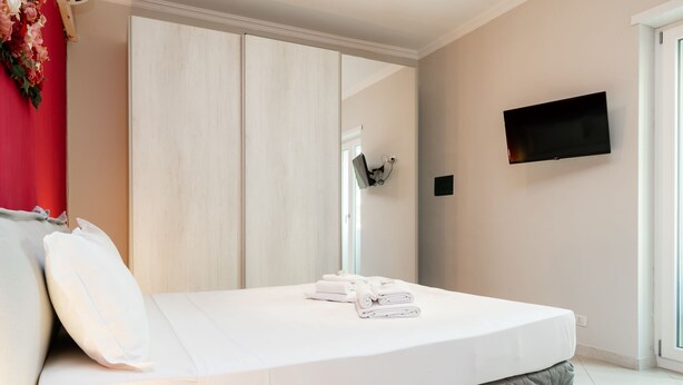 A bedroom with a bed, a TV mounted on the wall, and a wardrobe. - Romantic Malatesta in Rome (Rome)