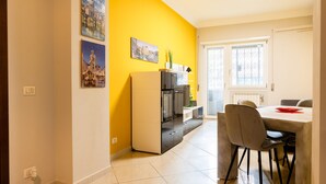 A modern kitchen with a yellow accent wall, a dining area with a table and chairs, and a refrigerator. - Romantic Malatesta in Rome (Rome)