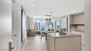 A modern kitchen with a central island, pendant lighting, and a view of the city.