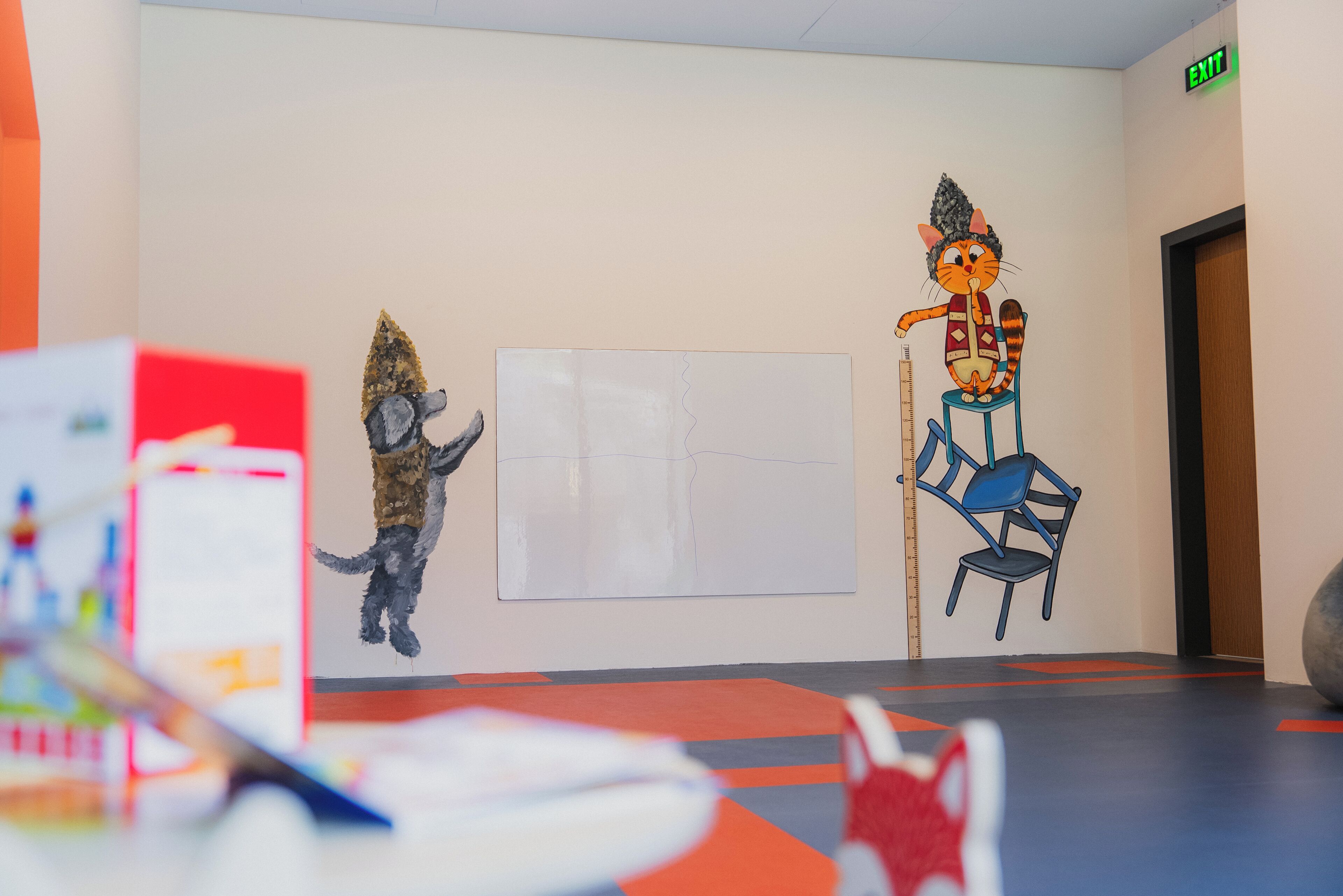 A modern interior with a large abstract painting, a colorful rug, and a playful cat mural.