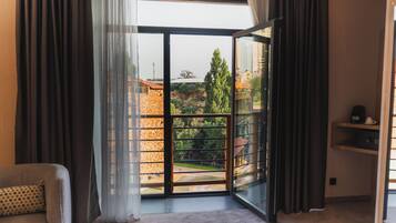Una habitación con un amplio ventanal corredera que da a un balcón con vistas a edificios y árboles.