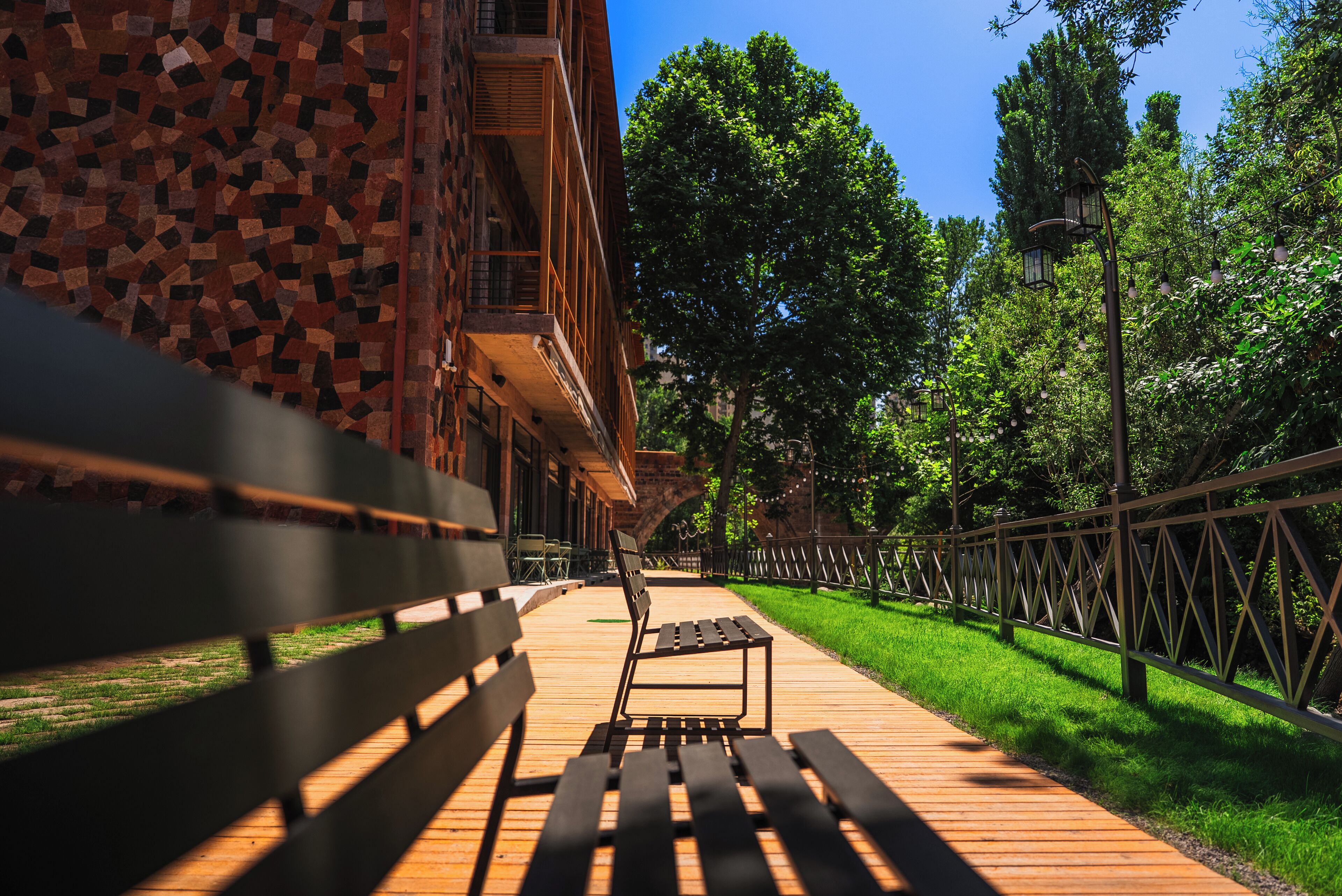 A wooden bench on a pathway leading to a building with a mosaic facade.