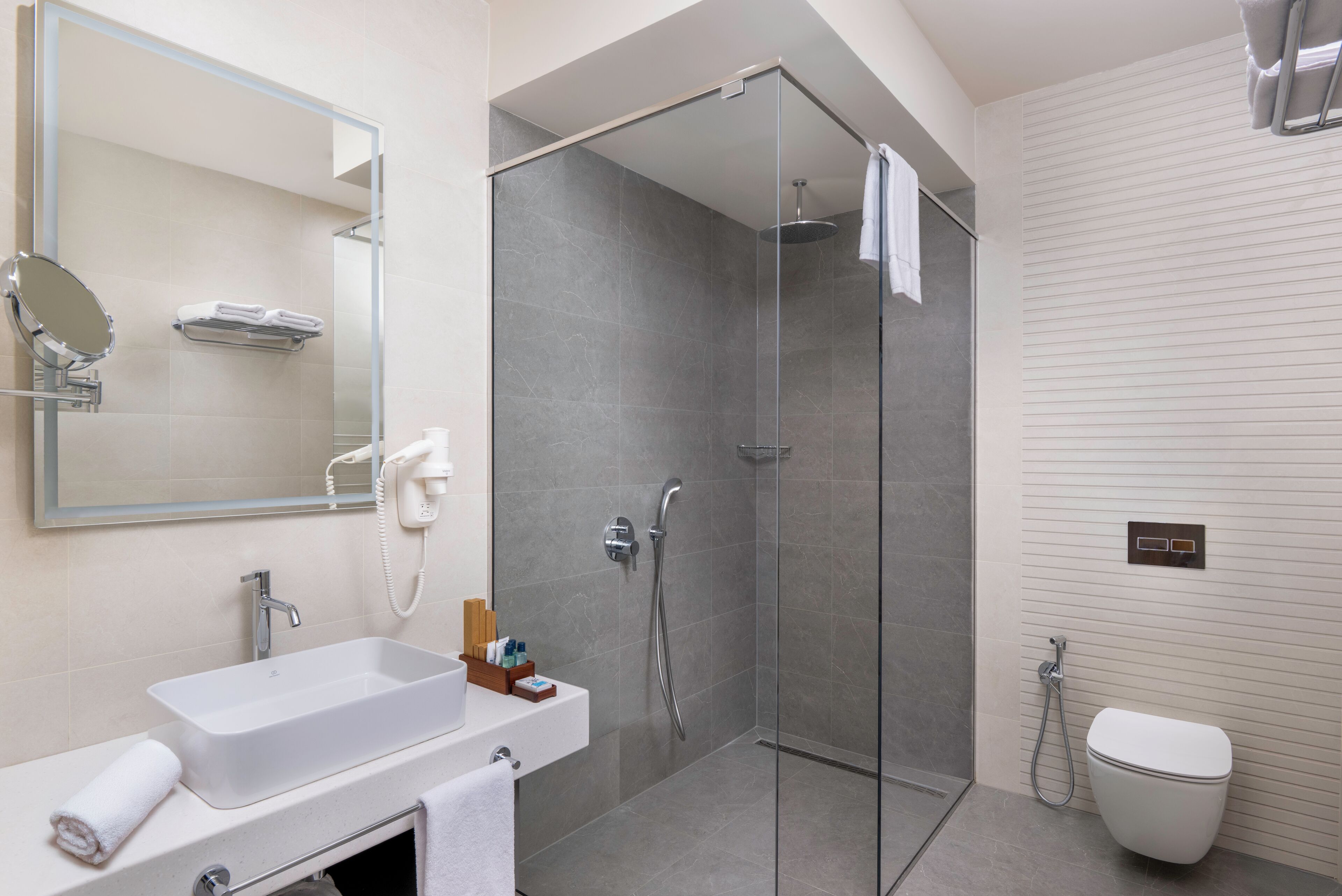Een moderne badkamer met een douchecabine van glas, een wit wastafelmeubel en een toilet.