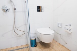 Een badkamer met douche, toilet en prullenbak.