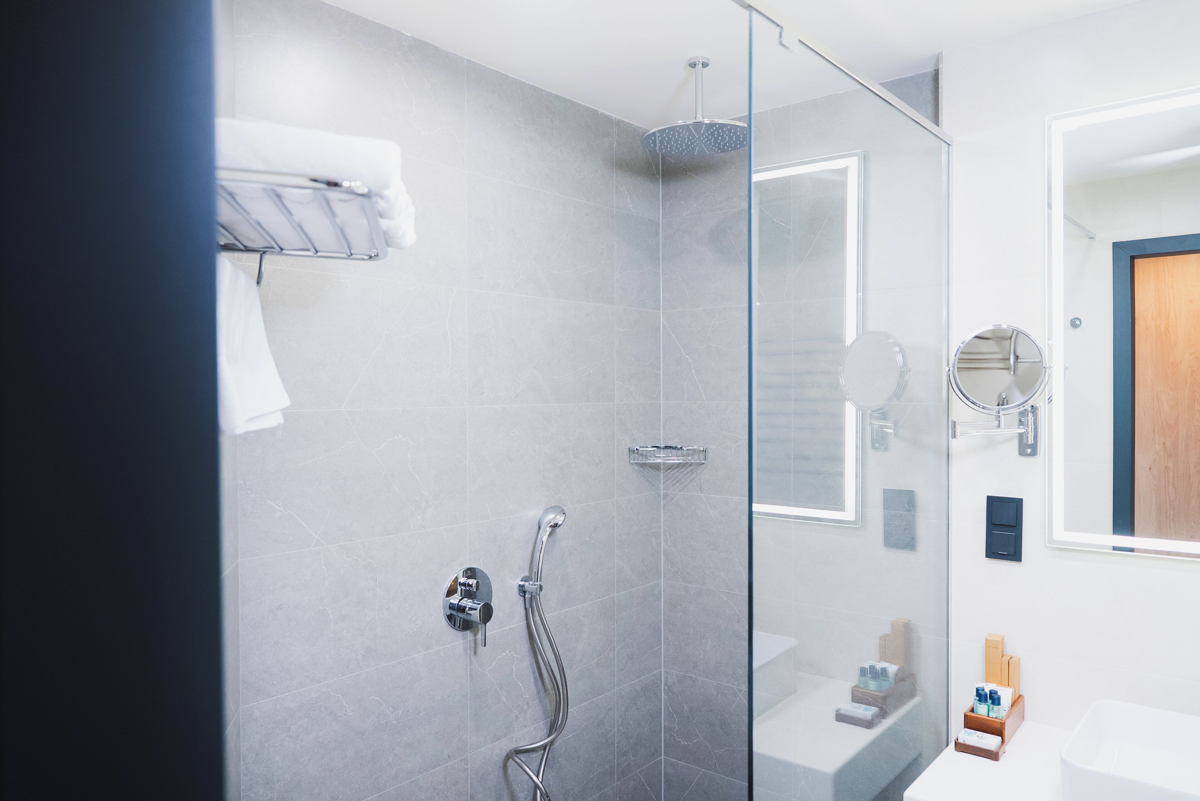 A modern bathroom with a glass-enclosed shower, a white sink, and a mirror.
