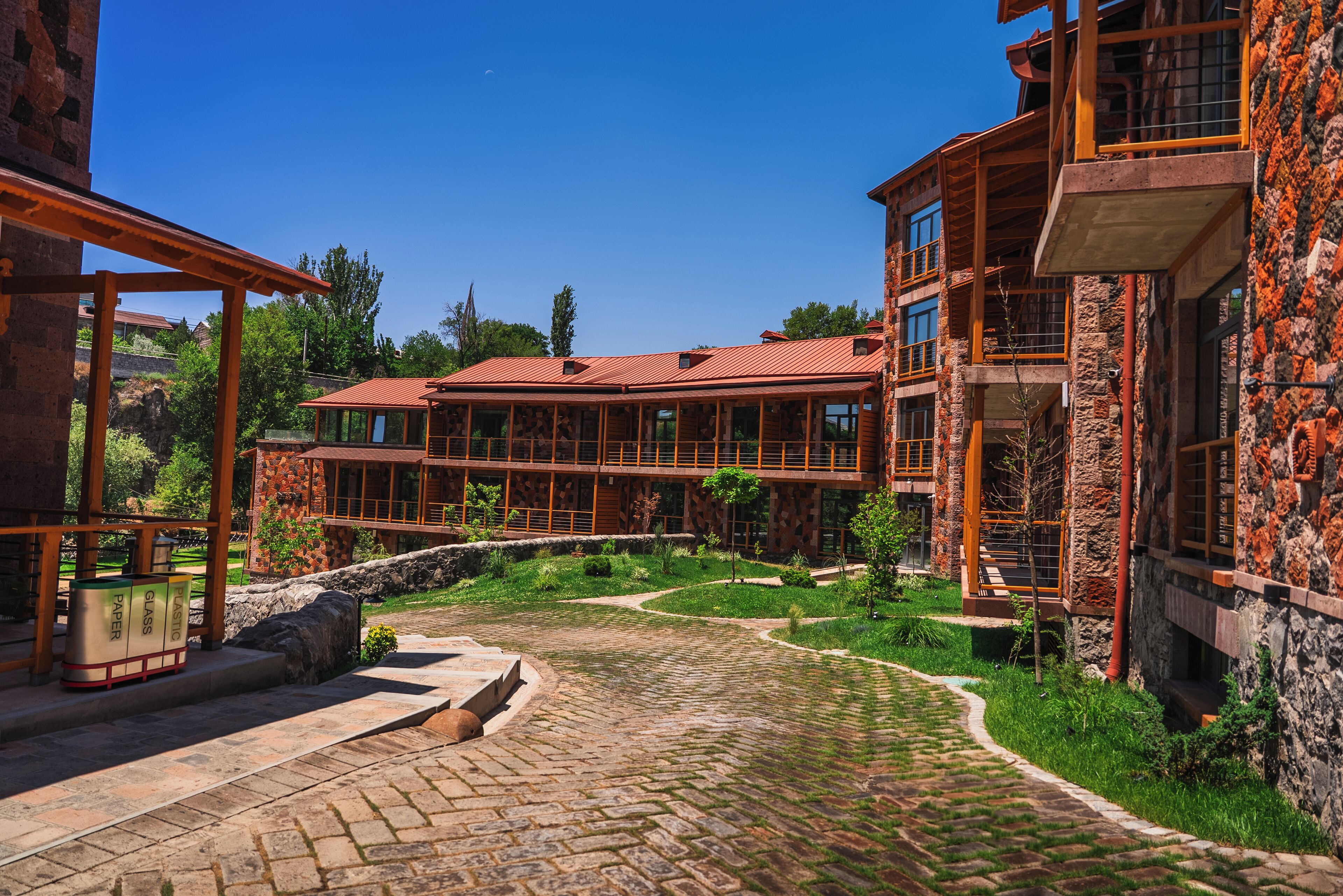A multi-story building with a stone facade, a red-tiled roof, and a courtyard with a cobblestone pathway.