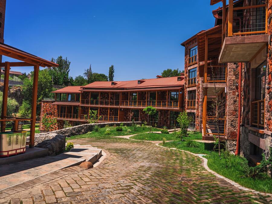 A multi-story building with a stone facade, a red-tiled roof, and a courtyard with a cobblestone pathway.