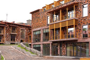 Een modern gebouw met een gevel van natuursteen, grote ramen en een trap naar de ingang.