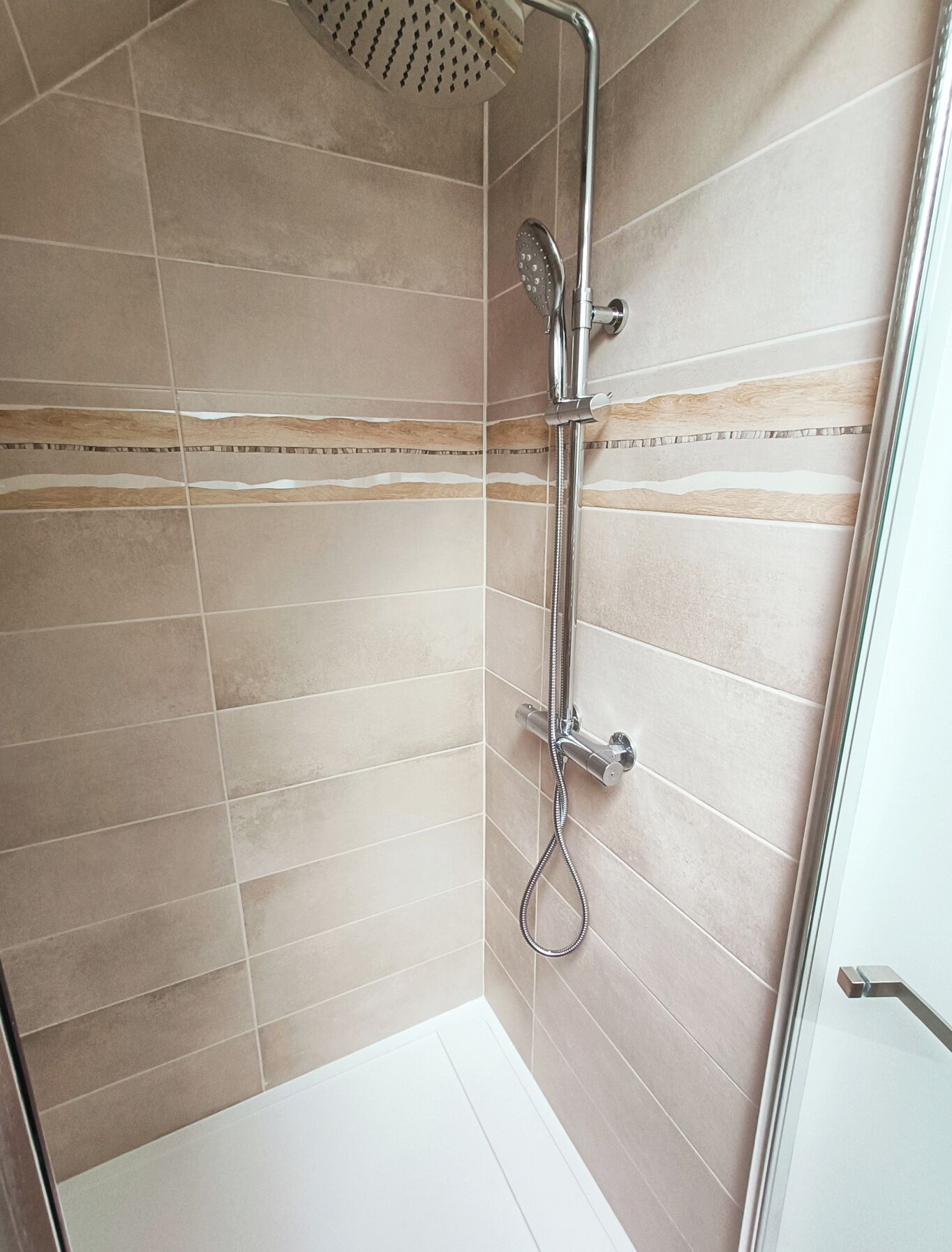 Un espacio de ducha con un cabezal de ducha de mano y un grifo empotrado en la pared.