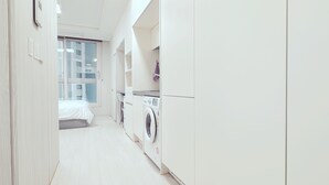 A modern, white-walled bedroom with a large window, a washing machine, and a bed. - The Time Hotel (Incheon)