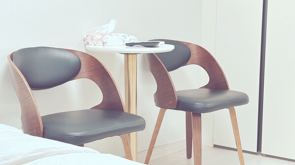 Two modern chairs with wooden and leather design, a small round table with a tissue box, and a white wall. - The Time Hotel (Incheon)