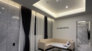 A modern hotel room with a beige sofa, a coffee table, and marble flooring. - Hotel Island (Ansan)