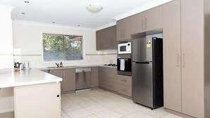 Una cocina moderna con electrodomésticos de acero inoxidable, armarios color beige y un amplio ventanal que proporciona luz natural.