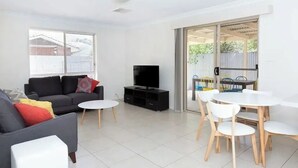 Una sala moderna con sofá, televisión y comedor.