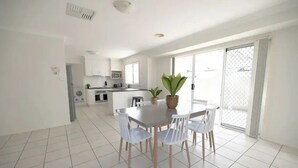 Una cocina moderna con armarios blancos, una mesa de comedor con sillas y un ventanal con vistas.