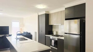 A modern kitchen with a central island, built-in oven, and stainless steel appliances. - Welcome to our stylish 3BR villa, perfect for an escape (Wagga Wagga)
