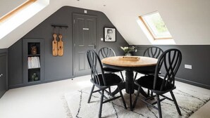 A dining area with a round table, black chairs, and a white rug. - Idyllic Cottage in the heart of The South Downs (Haslemere)