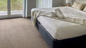 A hotel room with a large bed, a balcony with a view, and a ceiling fan. - Discover urban living in our contemporary townhouse! (Wagga Wagga)