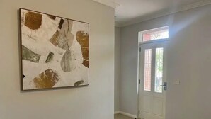 A hallway with a white door, a framed abstract painting on the wall, and a carpeted floor. - Discover urban living in our contemporary townhouse! (Wagga Wagga)