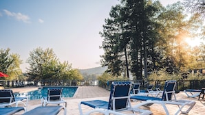 A poolside area with lounge chairs and a wooden deck.