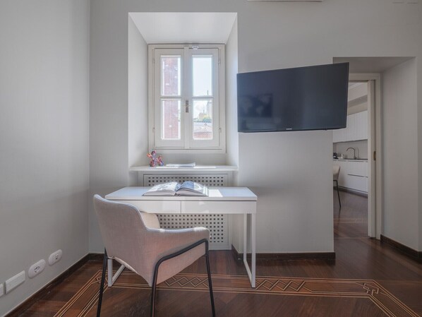 A modern room with a white desk, a chair, a window, and a flat-screen TV mounted on the wall. - Chic & Quiet Apartment in San Babila (Milan)