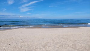A sandy beach with gentle waves and a clear blue sky.