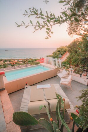 A pool area with lounge chairs and a view of the sea. - Villa Luna (Campulongu)