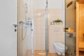 Ein modernes Badezimmer mit einer gläsernen Duschkabine, einer weißen Toilette und einem Holzbadezimmer-Möbel.