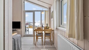 A cozy room with a wooden interior, a dining table with chairs, a television, and a view of the outside. - Cozy vacation home Harzer Nest with sauna, terrace and panoramic view in the Harz Mountains (St. Andreasberg)