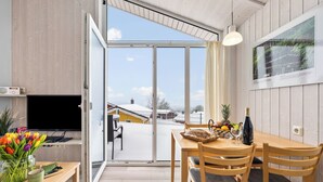 A modern kitchen with a large window, wooden furniture, and a dining area with a table set for two. - Cozy vacation home Harzer Nest with sauna, terrace and panoramic view in the Harz Mountains (St. Andreasberg)