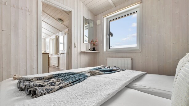 A bedroom with a bed, a window, a mirror, and a radiator. - "Escape to the Harz: Cozy vacation home with panoramic views!" (St. Andreasberg)